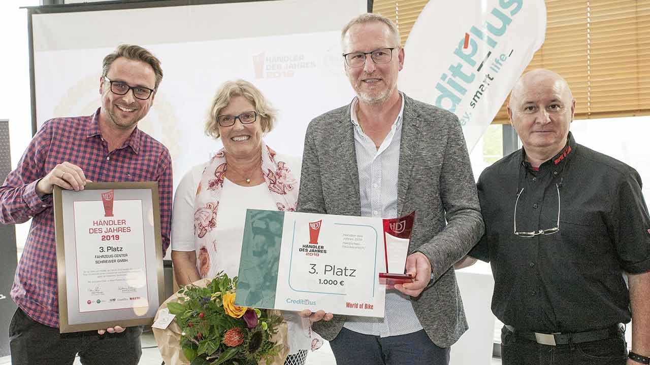 Patrick Rittich (Creditplus, li.) hielt die Laudatio auf den diesjährigen Drittplatzierten, das Fahrzeug-Center Schriewer, und überreichte Dagmar Calmer und Siegfried Schriewer-Calmer einen Scheck über die von Creditplus spendierte Siegprämie von 1.000 Euro. World of Bike-Verleger Klaus Hüttinger (re.o.) steuerte Pokal und Urkunde bei.